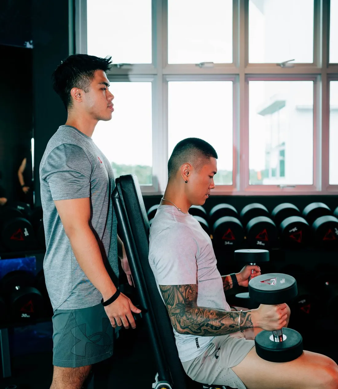 A Level Up trainer spotting a member on a dumbbell press